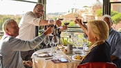 A restaurant staff member toasting a glass of wine with a table of Guests