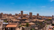 Vista panorámica de una ciudad histórica con edificios de piedra, techos y torres de terracota