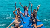 Homens e mulheres jovens sentados em um tapete aquático que flutua no mar