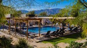 A pool surrounded by awning covered lounge chairs
