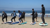 Visitantes practicando su postura mientras están sobre las tablas de surf en la playa de Ensenada, México.