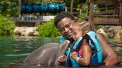 A father and daughter interact with a dolphin while in the water