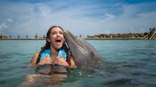 A Guest swims with a dolphin in the water