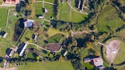Una extensa propiedad con edificios históricos, campos abiertos y vegetación