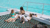Uma mãe e seus dois filhos saboreando bebidas a bordo de um barco turístico em Grand Cayman