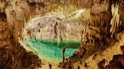 Uma abertura espaçosa nas cavernas de cristais Cayman Crystal Caves, com uma piscina de água e estalactites suspensos