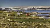 A sparsely populated rural area next to water and patches of snow