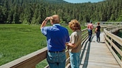 Guests standing on a wooden bridge while looking at a forest in Ketchikan, Alaska