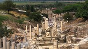 Turistas explorando las ruinas de una calle bordeada de columnas antiguas