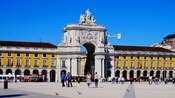 A plaza in front of a palace featuring a giant stone arch