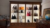 A wooden display cabinet full of leather purses