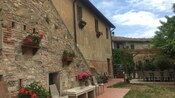 The courtyard and exterior of a 2 story Tuscan estate with a large table and ample seating
