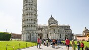A group of people standing near the Leaning Tower of Pisa in Italy
