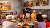 A server pouring a glass of wine in front of a table of Guests