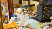 Creando un espacio de trabajo con piezas de cuero, herramientas, brochas, recipientes y una caja decorativa.