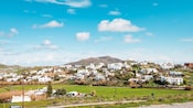 Buildings in Mykonos atop the hills and valleys of Greece against the mountains.