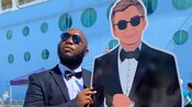 A man in a suit poses next to a carboard cut out of James Bond