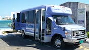 An accessible tour van parked near a body of water with a vehicle lift extending out from the side