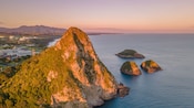 A large volcanic sea stack and other remnants, surrounded by the ocean near New Plymouth, New Zealand