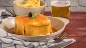 A plated serving of Francesinha, a Portuguese sandwich covered in melted cheese