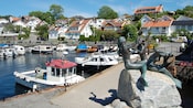 Boats docked in the harbor of Drøbak village with the Three Mermaids statue