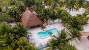 A large, hut like building next to a resort swimming pool, beside a beach