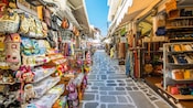 Estrecha calle adoquinada en Plaka con tiendas al aire libre a ambos lados