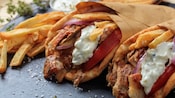 Gyro strips with some vegetables and sauce rolled in a pita with fries