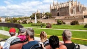 Guests on a double decker tour bus in front of the Catedral Basílica de Santa María de Mallorca