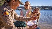 A National Parks Guide showing a dried sea dragon to a woman and a young girl
