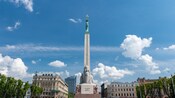 El Monumento a la Libertad de Letonia, un alto y estrecho pedestal coronado por la estatua de una mujer que levanta 3 estrellas