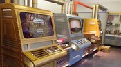 3 retro machines, each with a screen, several buttons and a counter table