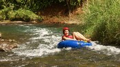 A woman in a life vest and helmet rafting down a river in an inflatable tube