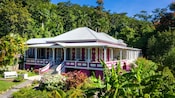 A homestead featuring a large house, surrounded by gardens and rainforest
