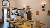 A wooden table set up for a cooking class with cutting boards, cheese graters, olive oil and spices