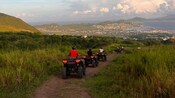 People traveling on ATVs on a dirt road in Basseterre, Saint Kitts and Nevis
