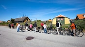 Un grupo de personas paradas junto a sus bicicletas y escuchando a un guía hablar