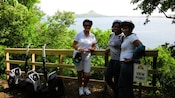 Three women with Segways posing at a viewpoint overlooking Caribbean waters