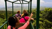 A group of people on an open air gondola over a rainforest in Saint Lucia