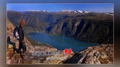 A hiker surveying the mountainous landscape of Jotunheimen National Park with the words ‘Skjolden’ and ‘der fjord moter fiell’