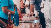 Bottles of rhum and many small shots, atop wooden barrels, as Guests prepare to enjoy a tasting