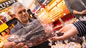 A shopkeeper pours dulse out of a bag into an outstretched hand