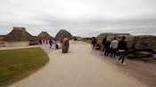 Tour groups exploring neolithic house exhibits at the Stonehenge Visitor Center