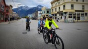 Três pessoas andando de bicicleta perto do Golden North Hotel em Skagway, Alasca