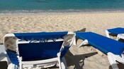 3 beach chairs on the shore of a sandy beach