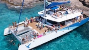 A catamaran, filled with people, floating in the water