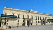 Uma estátua e um pátio de pedra em frente ao Palácio do Grão-Mestre em Valeta
