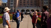A tour guide gestures toward a building sign reading The Empress