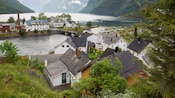 A Norwegian village full of houses along the waterfront near a stone bridge