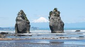 The Three Sisters, a rock formation in New Zealand, with Mount Taranaki in the distance 